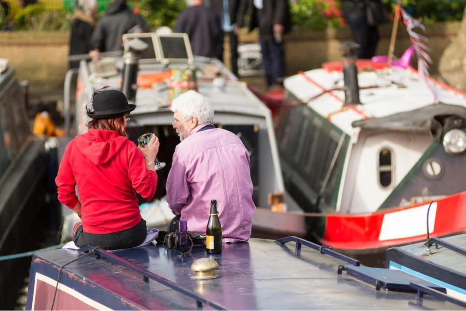2 people drinking and talking whilst sat on a narrowboat