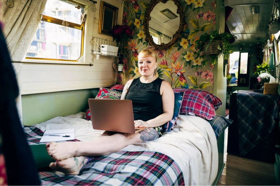 Woman using laptop on bed in narrowboat