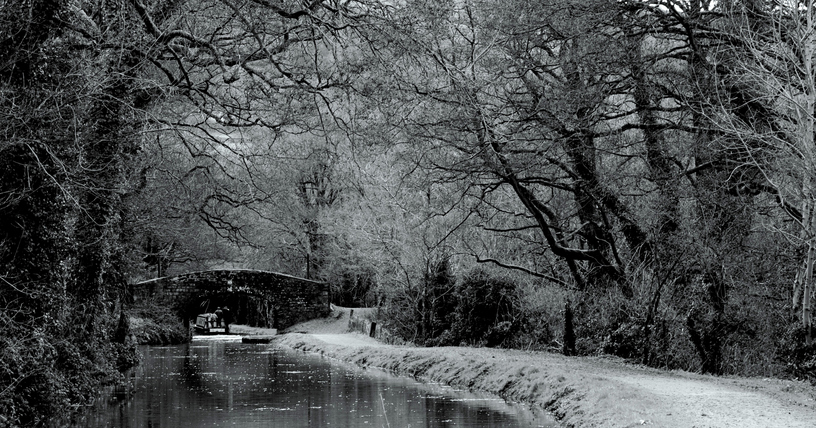 Photo of a canal, narrowboat and canal bridge during the winter