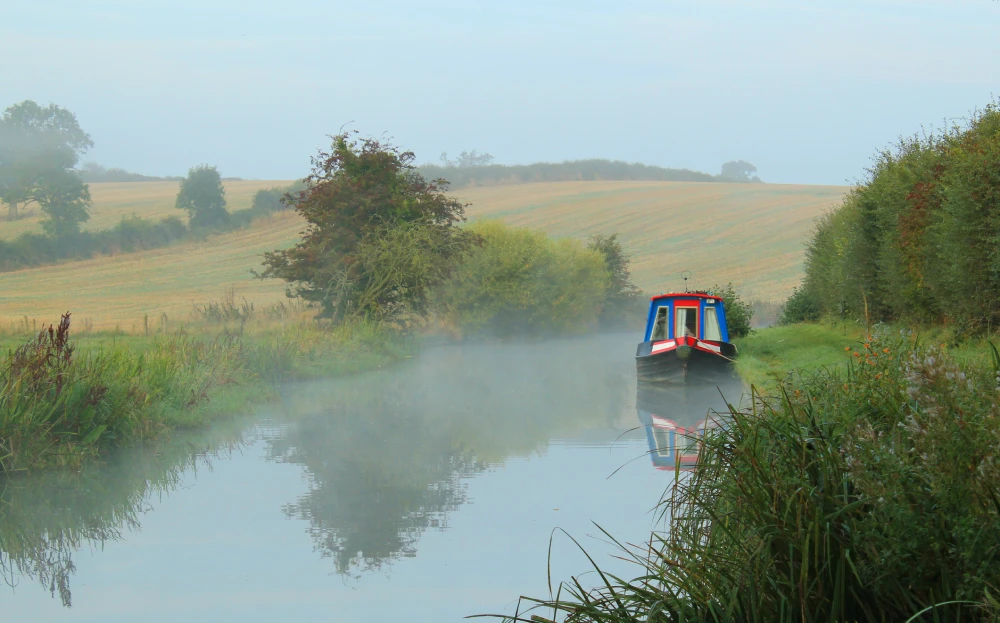 Narrowboat moored up at the side of the narrow canal